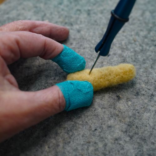 thimble tape on fingers protecting them from stabs from the felting needle